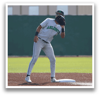 A baseball player in a white uniform is bending over to catch a ball. AI generated content