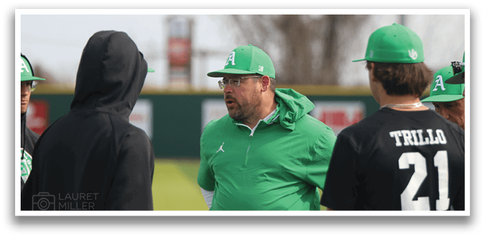 A group of men wearing green hats and black shirts are standing on a field. One man is wearing a green jacket and talking to the others. AI generated content