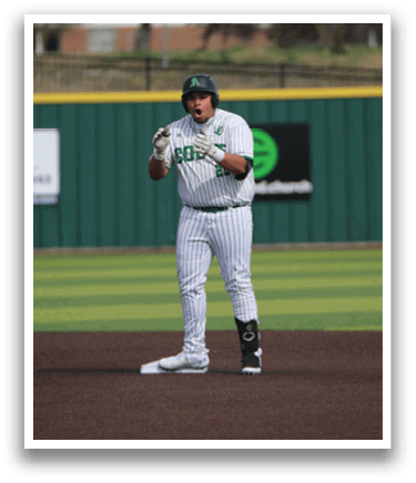 A baseball player is standing on the field, wearing a green and white uniform. He is holding a baseball bat and appears to be waiting for the next play. AI generated content