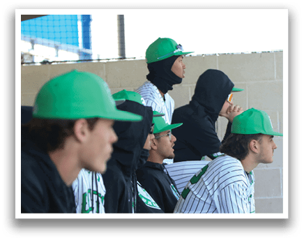Baseball players wearing green hats and black jackets sit on a bench. AI generated content
