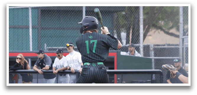 A baseball player in a black and green uniform is swinging a bat. Description generated by AI