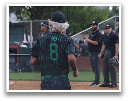 A baseball player wearing a green shirt with the number 8 on it. Description generated by AI
