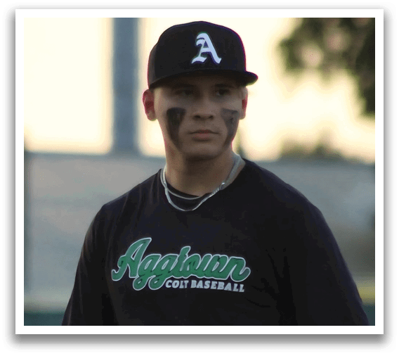 A baseball player wearing a black shirt with the word “Aggie" on it. Description generated by AI