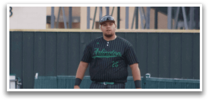 A man wearing a green shirt and black pants is walking on a baseball field. Description generated by AI