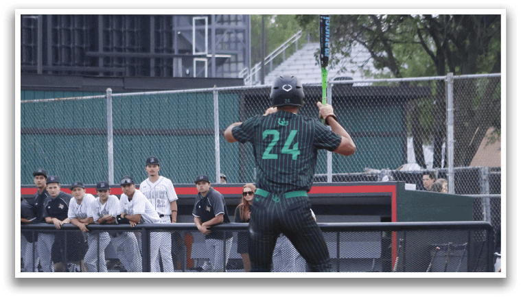 A baseball player in a green shirt and black pants is swinging a bat. Description generated by AI