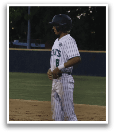 A baseball player wearing a white and green uniform stands on the field. Description generated by AI