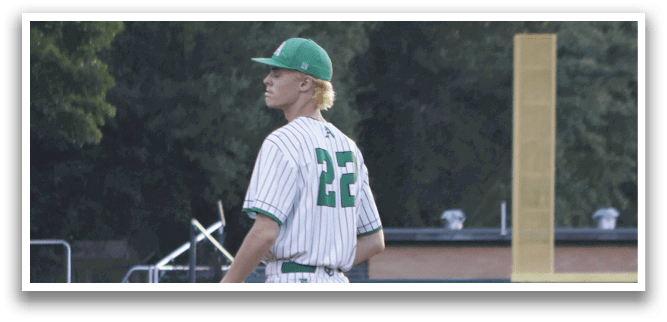 A baseball player in a white and green uniform stands on the field. Description generated by AI