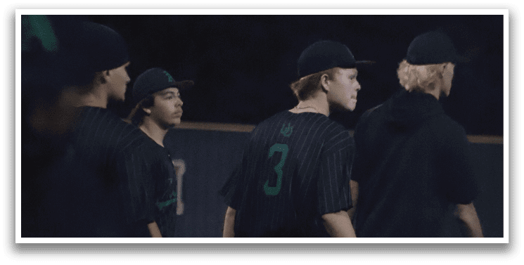 A group of baseball players wearing black shirts and green numbers on the back. Description generated by AI