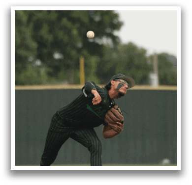 A baseball player in a black shirt and white shoes is pitching a ball. Description generated by AI