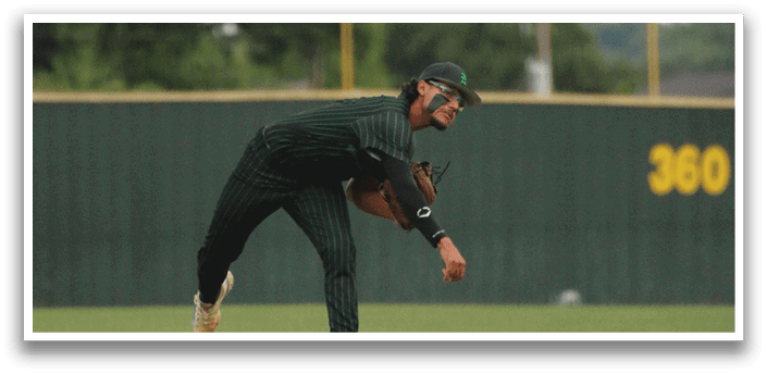 A baseball player in a green shirt and black hat is throwing a ball. Description generated by AI