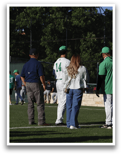 A man wearing a green shirt and a green hat is talking to a baseball player. Description generated by AI