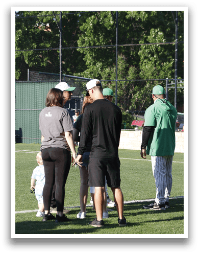 A group of people standing on a baseball field. Description generated by AI