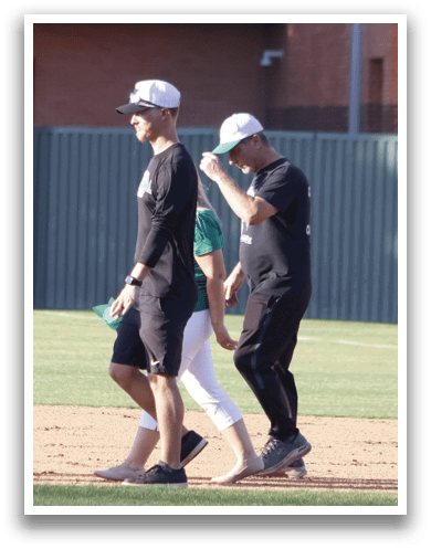 A man wearing a baseball uniform walks on a field. Description generated by AI