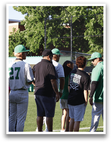 A man wearing a green shirt and a green hat is talking to a baseball player. Description generated by AI