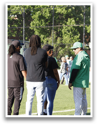 A group of people standing on a baseball field. Description generated by AI