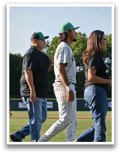 A man wearing a baseball uniform walks on a field. Description generated by AI