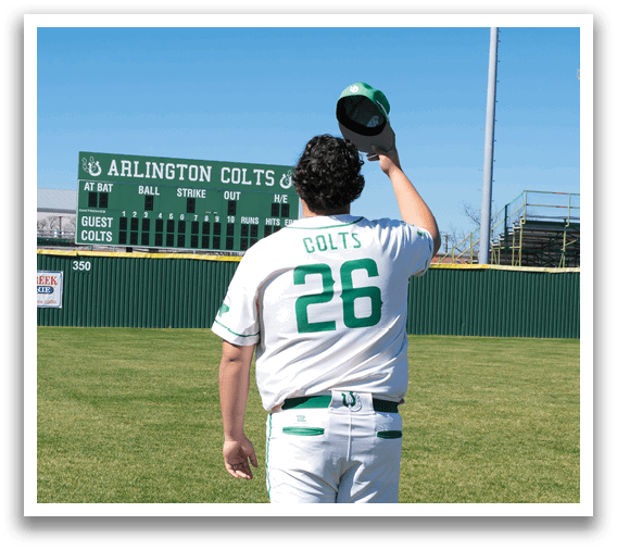 A baseball player wearing a green and white uniform stands on a baseball field. Description generated by AI