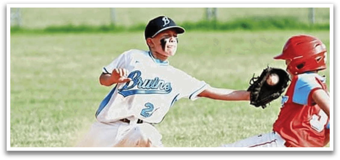 A boy in a blue shirt slides into a base. Description generated by AI