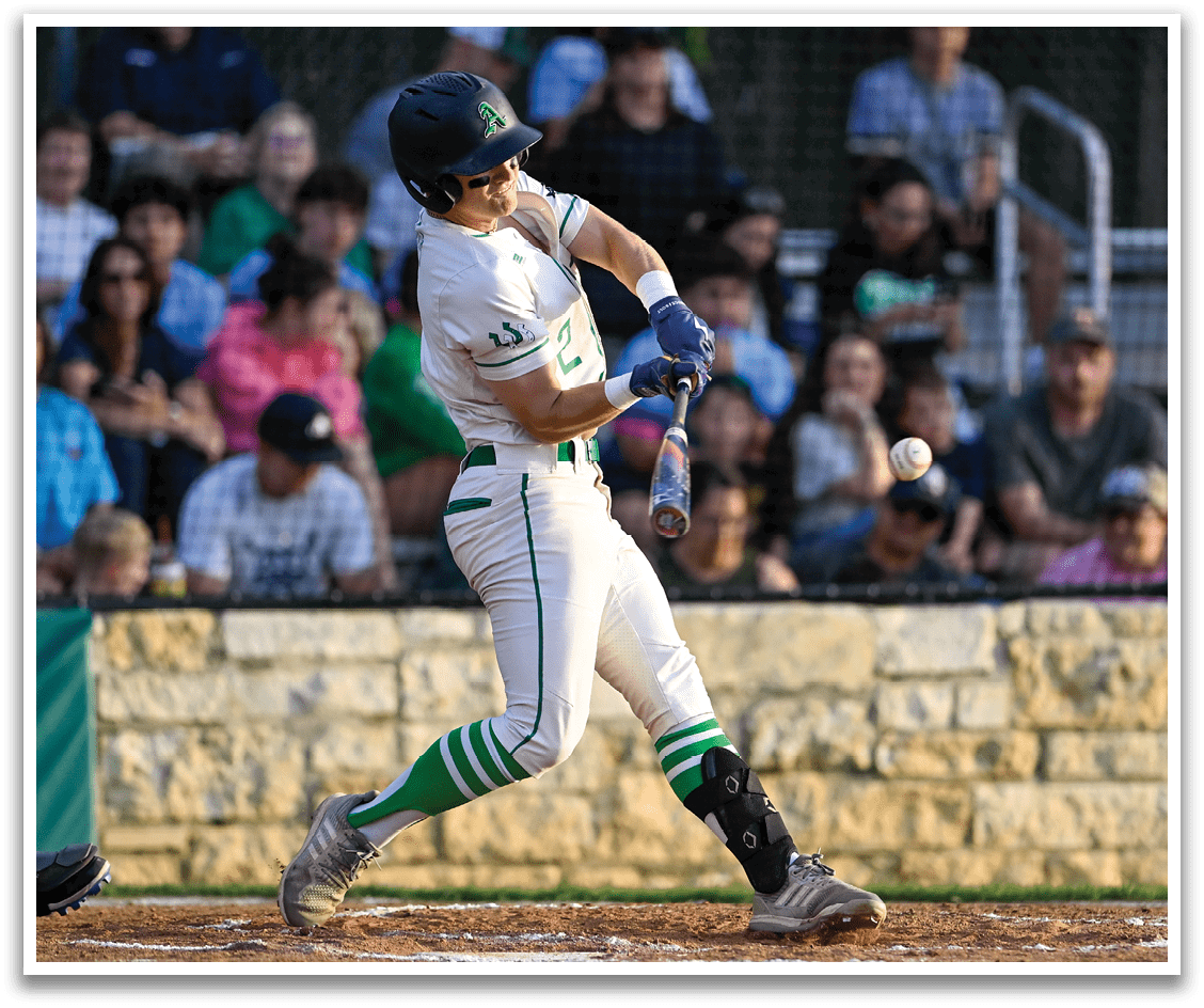 A baseball player in a white uniform is swinging a bat at a ball. Description generated by AI