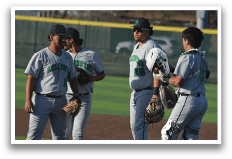 Four baseball players wearing grey uniforms are standing on a field. They are holding baseball gloves and talking to each other. AI generated content