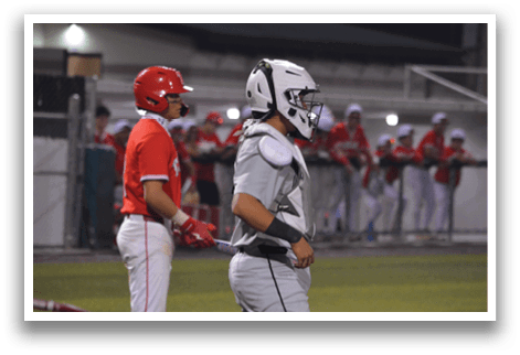 A baseball player in a grey uniform is holding a bat, standing on a field with other players. AI generated content