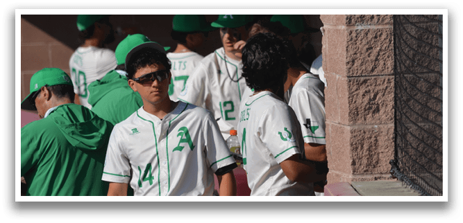 A group of baseball players wearing green and white uniforms are standing next to a fence. AI generated content