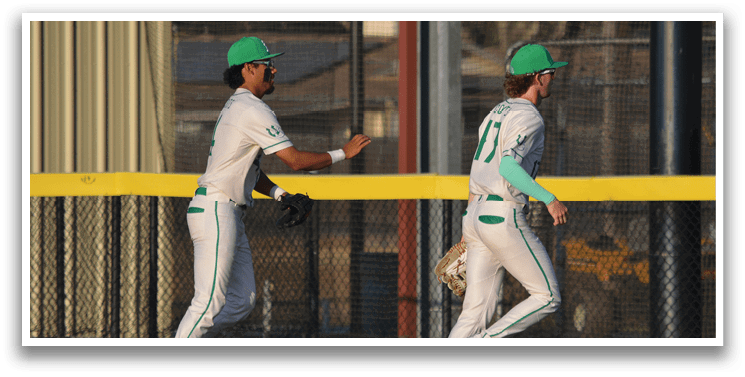 Two baseball players wearing green and white uniforms are walking on the field. AI generated content