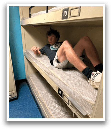 A man is laying on a bunk bed, resting on a mattress. AI generated content