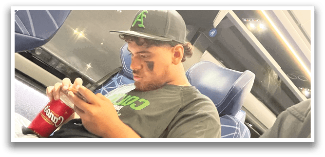 A man wearing a green shirt and a black hat is sitting on a bus. He is holding a red cup in his hand. AI generated content