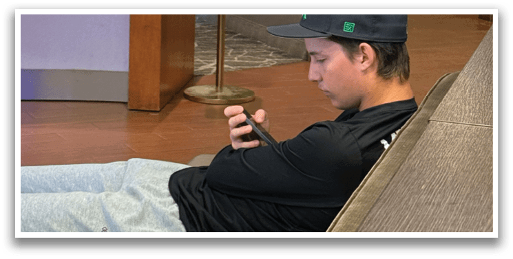 A man is sitting on a couch, looking at his cell phone. AI generated content