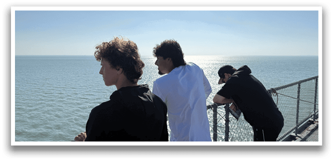Three people are standing on a boat, looking out at the ocean. AI generated content