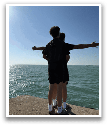 Two people standing on a rock, one with their arms outstretched, the other with their arms around the first. AI generated content
