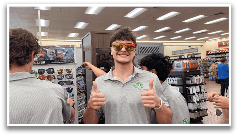 A man wearing sunglasses and a grey shirt gives a thumbs up in a store. AI generated content