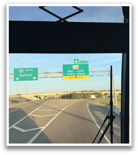 A bus driving on a highway with a green sign above it. AI generated content