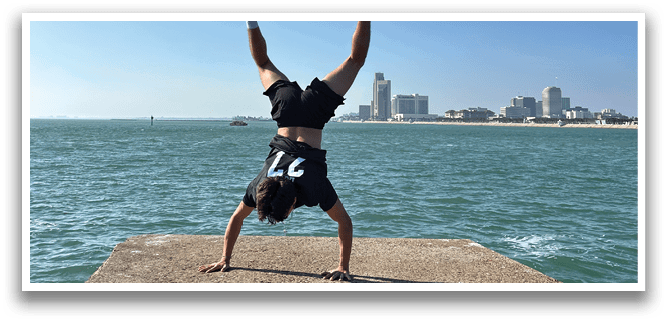 A man is doing a handstand on a cement wall overlooking the ocean. AI generated content