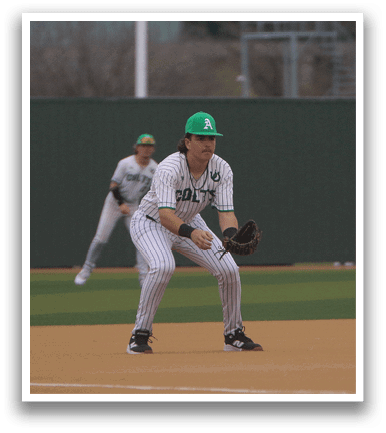 A baseball player is in the field, wearing a green hat and a white and green uniform. He is holding a baseball glove, ready to catch the ball. Another player is in the background, also wearing a baseball glove. AI generated content