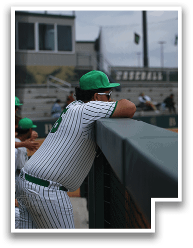 A baseball player wearing a green hat and a white uniform is leaning on a fence. AI generated content