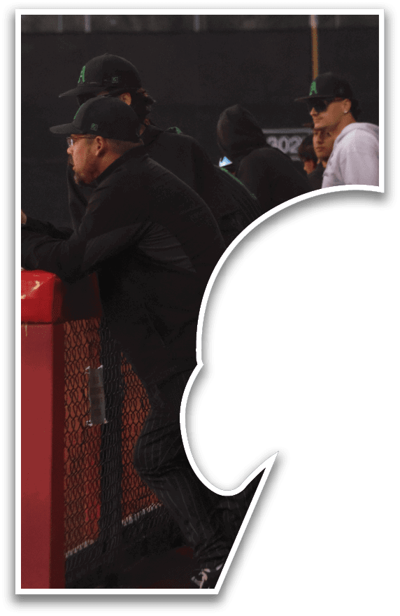 A group of men wearing green hats and black clothing are standing in front of a fence. AI generated content