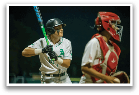 A baseball player in a white uniform is holding a bat, ready to swing. The catcher is wearing a red helmet and is positioned behind the batter, waiting for the ball. AI generated content