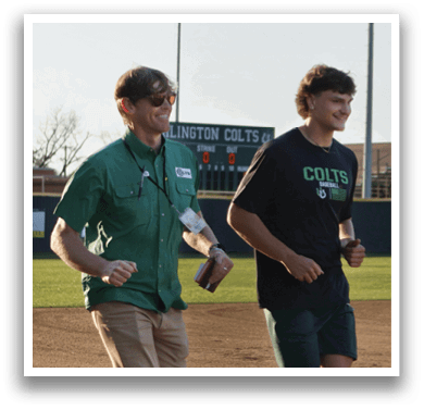 Two men are running on a field, one wearing a green shirt and the other wearing a black shirt. AI generated content