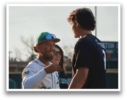 Two men are standing on a baseball field, one of them wearing a baseball uniform. They are shaking hands and smiling at each other. AI generated content