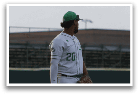 A baseball player wearing a green hat and white uniform. Description generated by AI