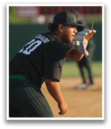 A baseball player in a black shirt and green pants is throwing a ball. Description generated by AI