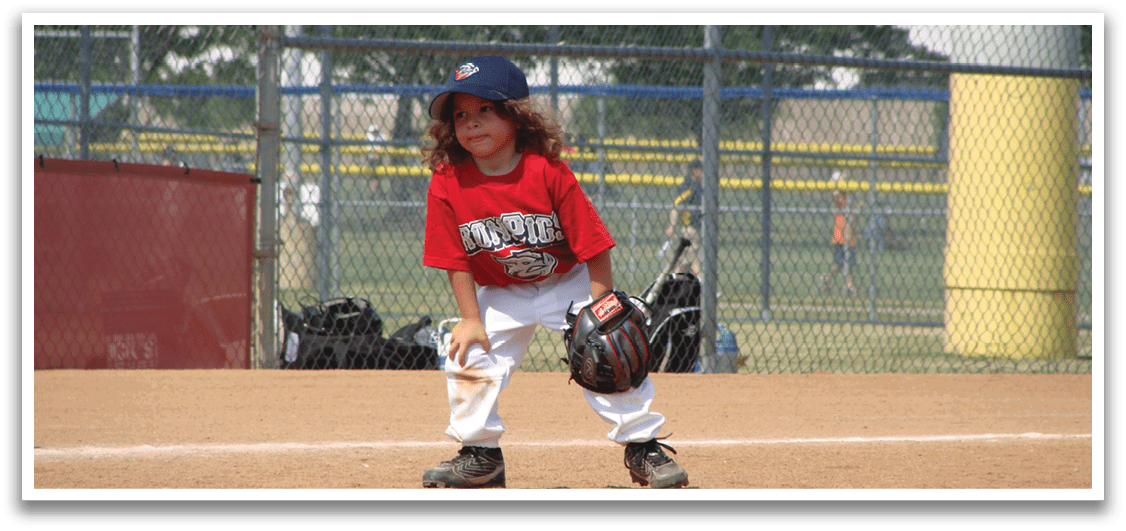 A young boy wearing a red shirt and white pants is playing baseball. Description generated by AI
