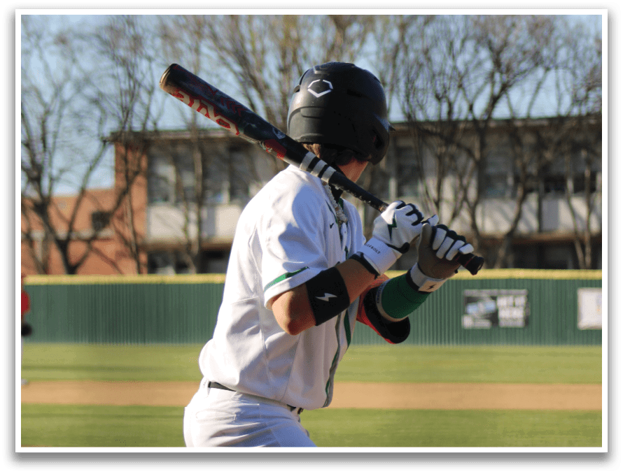 A baseball player in a white uniform is holding a bat and getting ready to swing. Description generated by AI