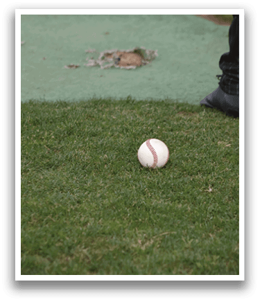 A baseball is on the ground. Description generated by AI