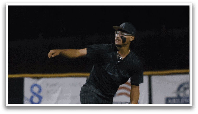 A baseball player in a black shirt and green hat is throwing a ball. Description generated by AI