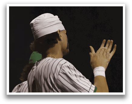 A baseball player wearing a white hat and green and white uniform. Description generated by AI