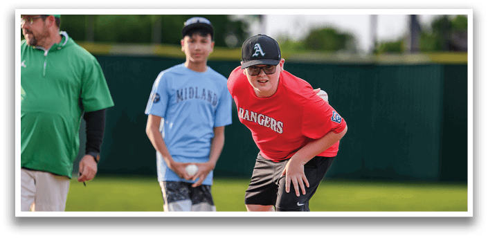 A boy in a red shirt is standing on a mound of dirt. Description generated by AI
