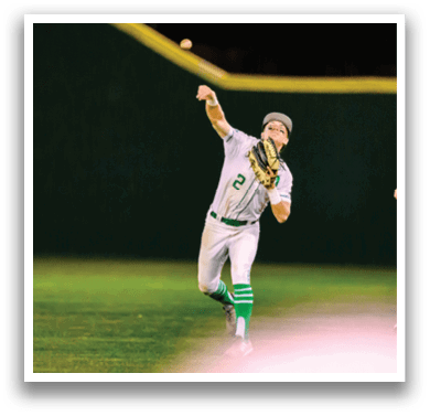 A baseball player wearing a white uniform and a green hat, throwing a ball. Description generated by AI